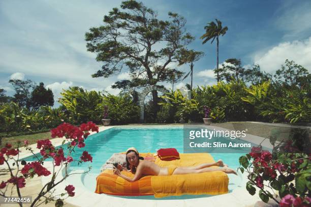 The former Pauline Haywood sunbathing on a lilo in a swimming pool designed by English artist Oliver Messel, Barbados, April 1976. Her family owned...