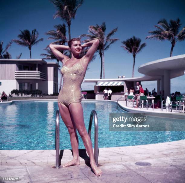 American swimmer and actress Esther Williams posing by the pool in a sparkly gold swimsuit, Florida, 1955.