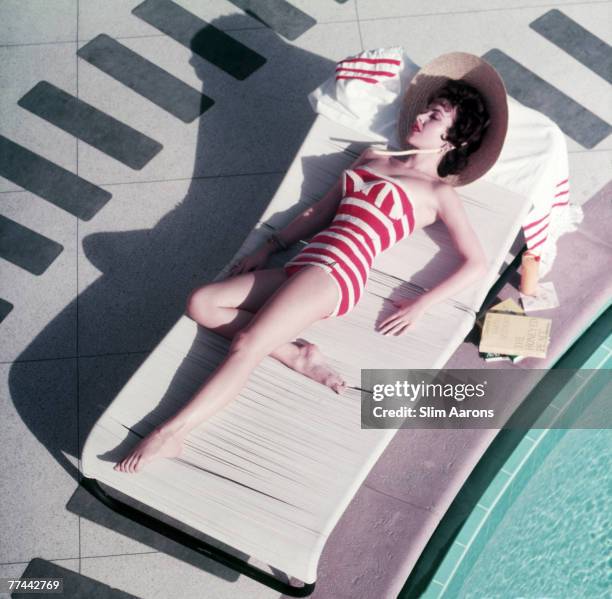 Austrian actress Mara Lane lounging by the pool in a red and white striped bathing costume at the Sands Hotel, Las Vegas, 1954. Beside her is a copy...