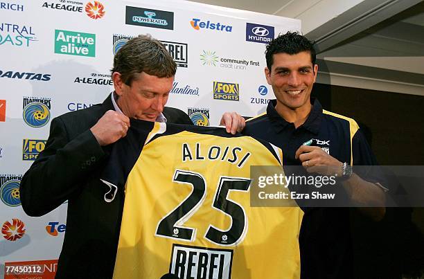 Central Coast Mariners Executive Chairman Lyall Gorman and John Aloisi hold up Aloisi's new jersey at a press conference announcing his signing for...