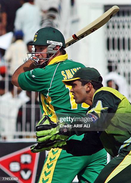 South African captain Graeme Smith eyes the ball after playing a shot as Pakistani wicketkeeper Kamran Akmal looks on during the third day-night...