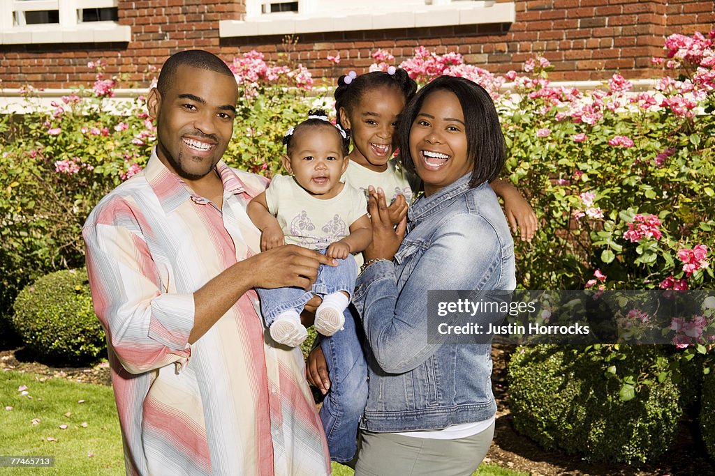 Photo of a young family standing together in their front yard, laughing.