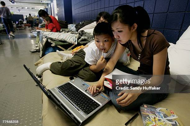 Fire evacuees Ying and Tony Huang work on a computer at Qualcomm Stadium October 23, 2007 in San Diego, California. The Witch Creek fire, which...