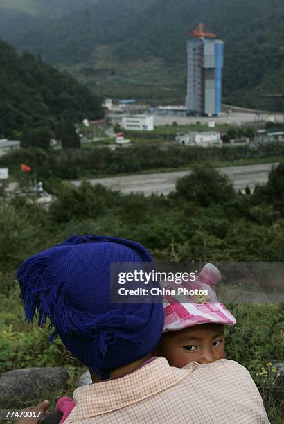 Woman holding her baby views the No. 3 Launching Tower, which will launch China's first lunar satellite at the Xichang Satellite Launch Center on...