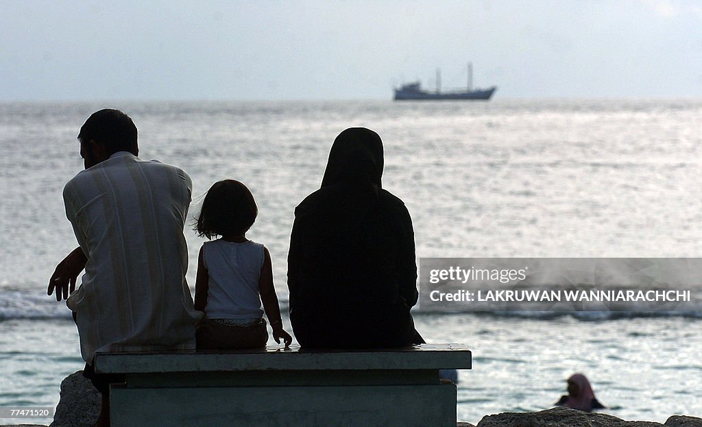 A Maldivian family sits near an artifici