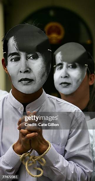 Protesters against the situation in Burma with hands tied wear masks with the face of Aung San Suu Kyi outside the Chinese Embassy on October 24,...