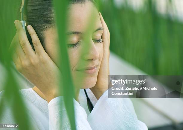 woman listening to headphones, eyes closed, hands over ears - hands over ears stock pictures, royalty-free photos & images