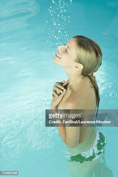 young woman standing under spray of water in pool, covering bare chest - bare bottom women - fotografias e filmes do acervo