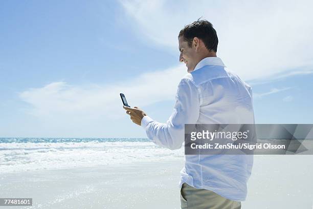 businessman dialing cell phone on beach - tutti i tipi di top foto e immagini stock