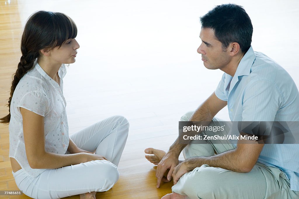 Man and woman sitting on floor, face to face