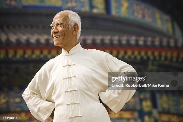 man with hands on hips looking away smiling - himmelstempel stock-fotos und bilder