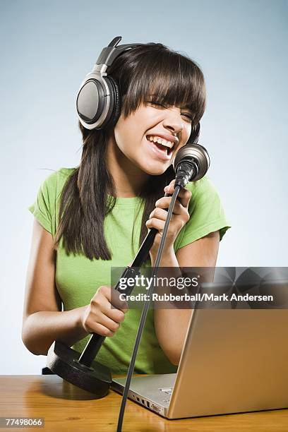 young woman recording into a microphone with headphones and a laptop - ot ストックフォトと画像