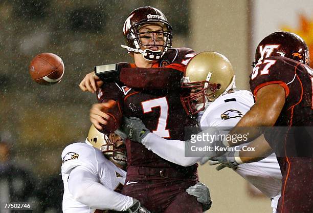 Quarterback Sean Glennon of the Virginia Tech Hokies sidearms a pass while getting tackled by defenders Nick Larkin and Jim Ramella of the Boston...