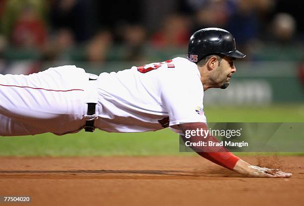 Mike Lowell of the Boston Red Sox slides into third base on a single hit by J.D. Drew during the fourth inning of Game Two of the 2007 World Series...