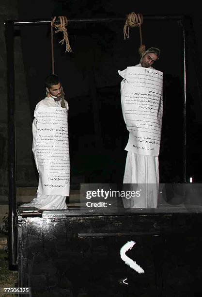 Two executed Syrian men hang from the gallows with a sign detailing their crimes wrapped around their bodies in the centre of the northern town of...