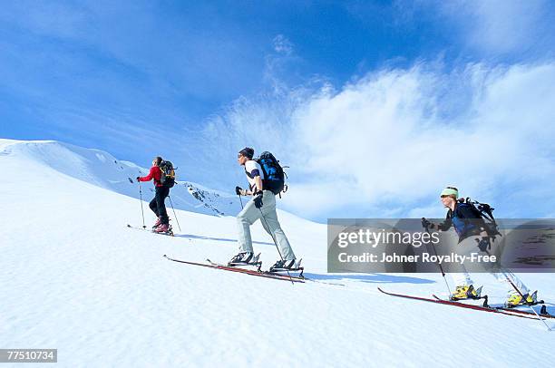 three skiers going up the ski slope storulvan jamtland sweden. - jamtland stockfoto's en -beelden