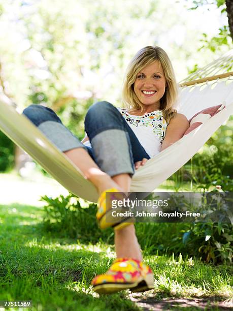 a woman wearing clogs sitting in a hammock stockholm sweden. - trädgård hängmatta bildbanksfoton och bilder