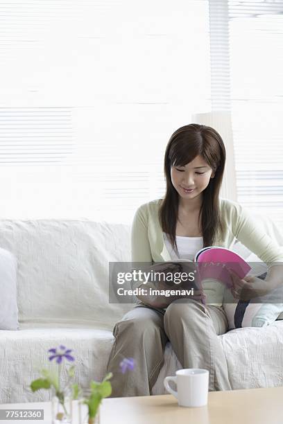 woman on sofa reading a magazine - coffee table reading mug stock pictures, royalty-free photos & images