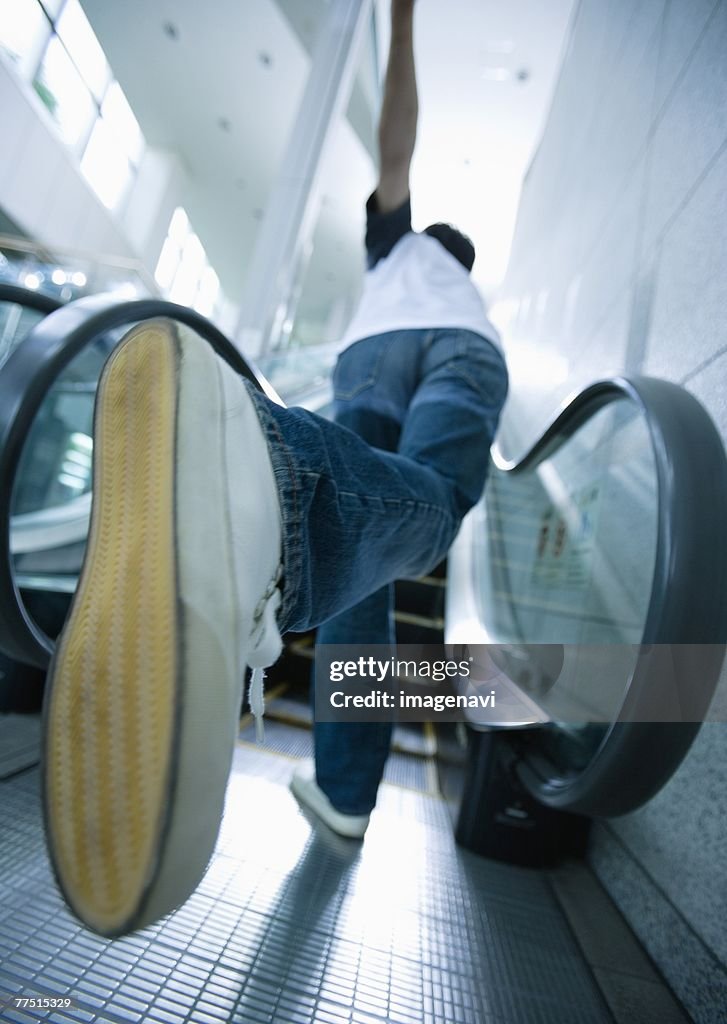 Young man running up escalator