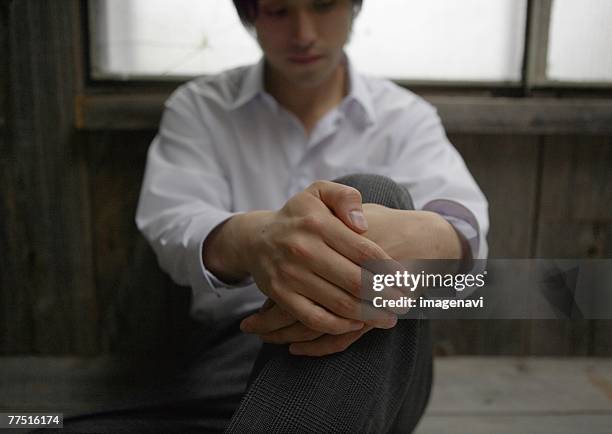 man sitting with arms around knee - mit dem gesicht nach unten stock-fotos und bilder
