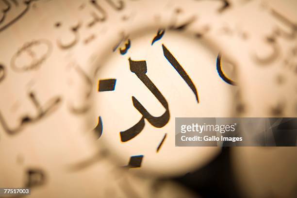 close up of arabic calligraphy through the eye of a magnifying glass. dubai, united arab emirates - arabic caligraphy stock pictures, royalty-free photos & images