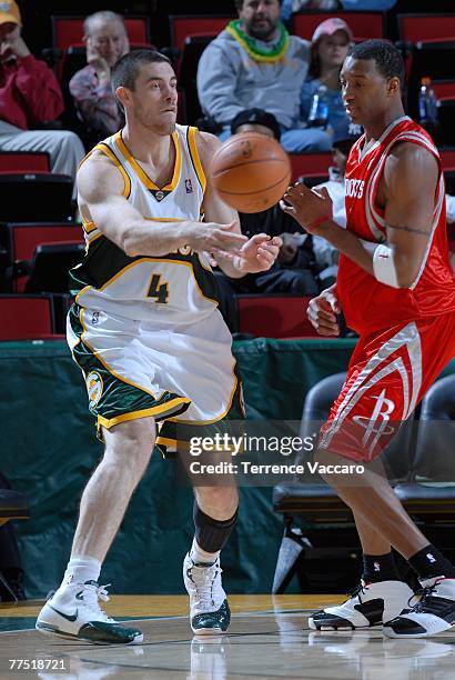 Nick Collison of the Seattle SuperSonics sends the ball past Tracy McGrady of the Houston Rockets during the game at Key Arena on October 20, 2007 in...