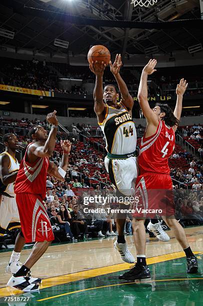 Kurt Thomas of the Seattle SuperSonics lays the ball up over Luis Scola and Tracy McGrady of the Houston Rockets during the game at Key Arena on...