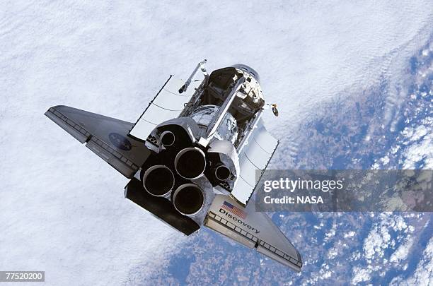 In this handout provided by NASA, Backdropped by a blue and white Earth, Space Shuttle Discovery approaches the International Space Station during...