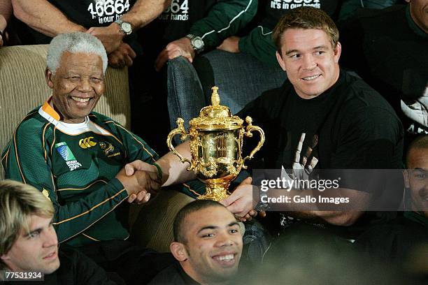 Former South Africa President Nelson Mandela poses with South Africa Rugby Union captain John Smit and the Webb-Ellis cup during the Springboks visit...