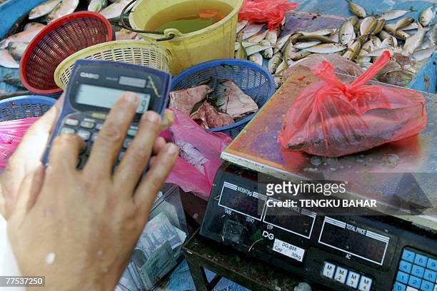 Fishmonger calculates a sale as a bag of fish sit on top of a scale at an outdoor wet market in Kuala Lumpur, 28 October 2007. Malaysia's economy is...
