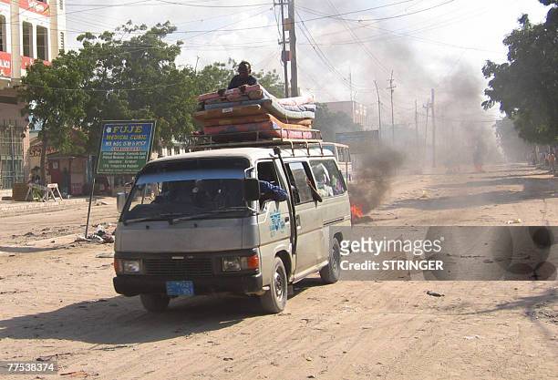 Van loaded with mattresses and residents of Mogadishu leaving the city drives past a burning barricade, 28 October 2007. Hundreds of families fled...