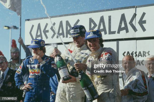 Australian racing driver Alan Jones showers photographers with champagne from the podium after driving the TAG Williams Racing Team Williams FW07C...