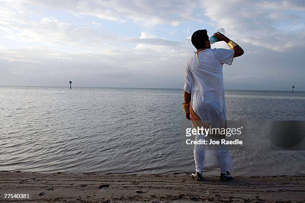 Hernan Castillo, who said he was dressed as Julius Caesar, greets the morning with a drink of water next to the ocean during Fantasy Fest October 28,...