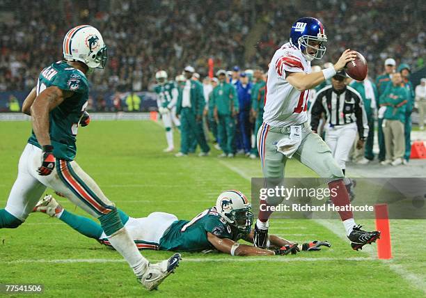 New York quarterback, Eli Manning outpaces Jason Taylor of the Dolphins to score the opening touchdown during the NFL Bridgestone International...