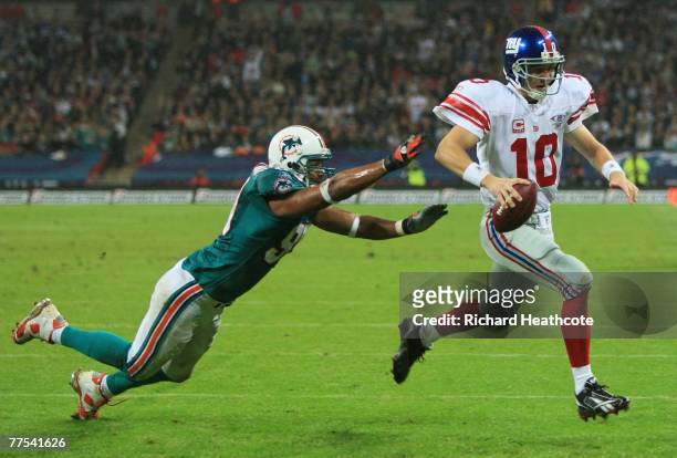 New York quarterback, Eli Manning outpaces Jason Taylor of the Dolphins to score the opening touchdown during the NFL Bridgestone International...