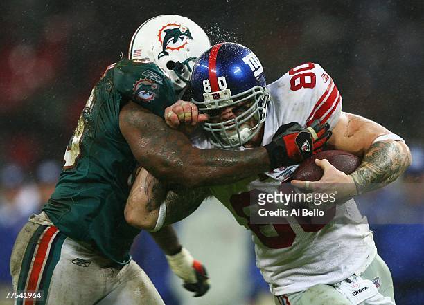 Derrick Pope of Miami Dolphins tackles Jeremy Shockey of New York Giants causing him to fumble during the NFL Bridgestone International Series match...