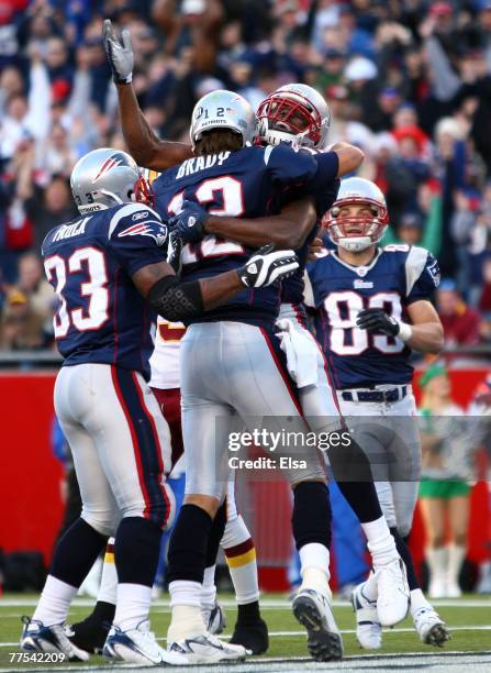 Randy Moss, Kevin Faulk and Wes Walker of the New England Patriots congratulate Tom Brady after Brady ran the ball in for a touchdown in the first...