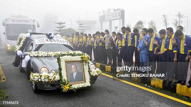 Genting employees pay their last respects as a hearse bearing the coffin of late gaming tycoon Lim Goh Tong drives past during a funeral procession...