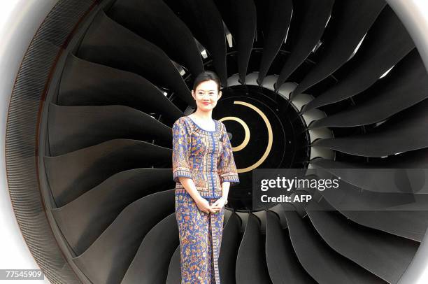 Cabin crew of Singapore Airlines poses next to one of the engines of the company's Airbus A380 passsenger plane parked at Sydney international...