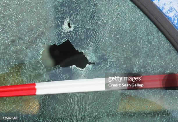 The shattered window of a car struck by a bullet is visible outside a branch of Postbank bank after an attempted robbery that left one guard dead...