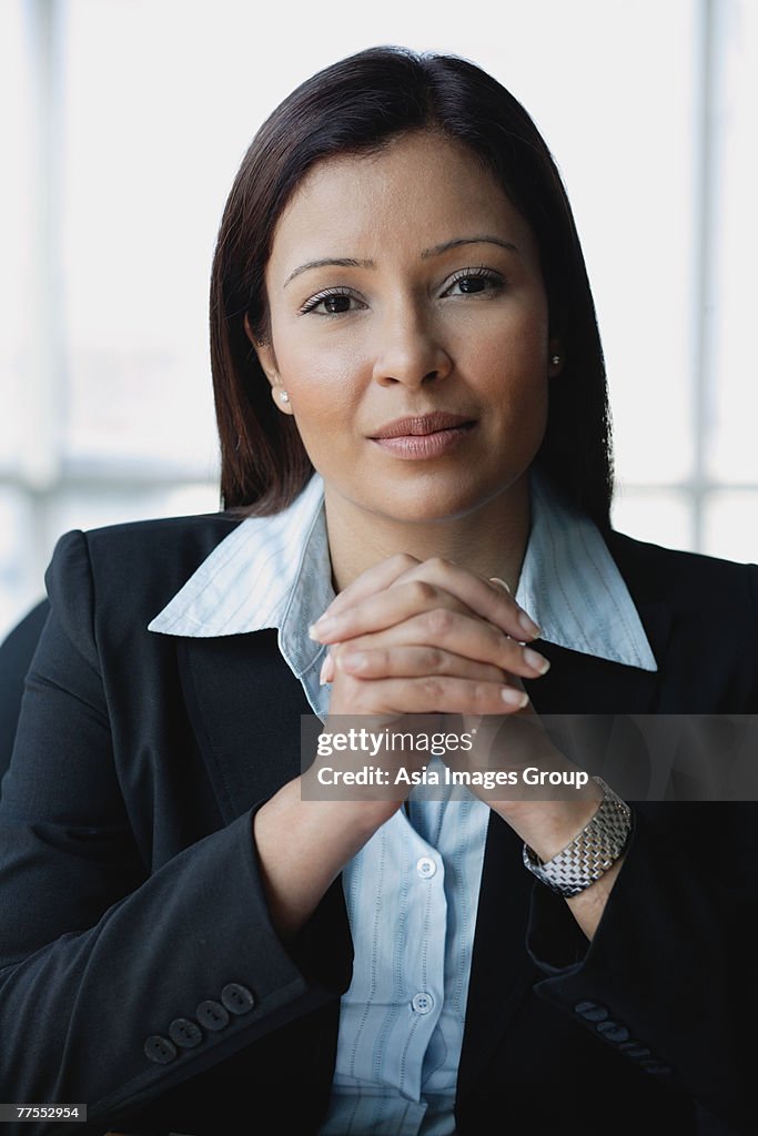 Businesswoman looking at camera, hands clasped, portrait