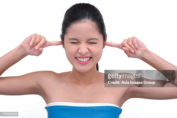 young woman with fingers in ears, eyes closed - woman fingers in ears stock pictures, royalty-free photos & images