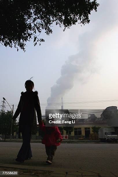 Chinese woman and her daughter pass by a power plant on October 30, 2007 in Beijing China. A report from the National Population and Family Planning...