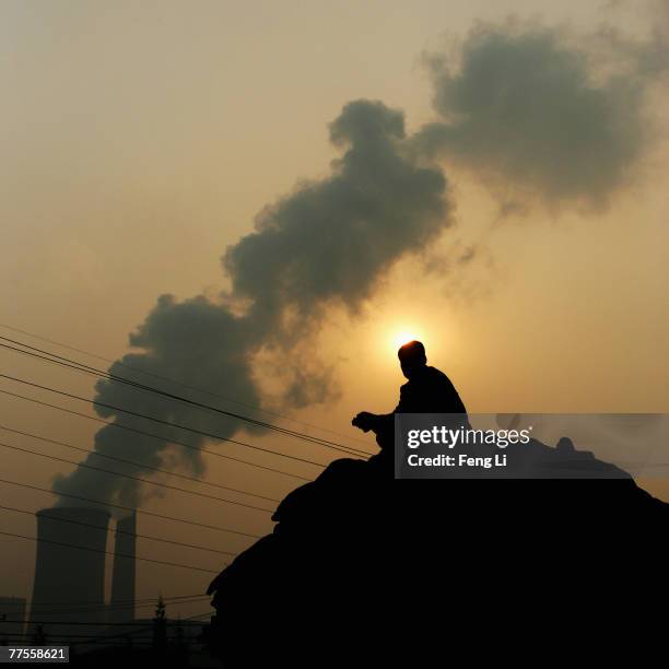 Chinese man squats on the truck goods near a power plant on October 30, 2007 in Beijing China. A report from the National Population and Family...