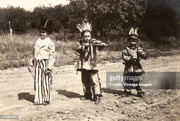 Portrait of three boysi n costume on a dirt road, Dorchester, Nebraska, early twentieth century. One is dressed as a Uncle Sam, in stripped trousers,...