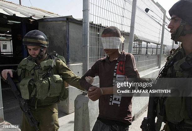 Blind folded and cuffed Palestinian youth is led away by Israeli soldiers after he was stopped allegedly carrying explosive material at the Hawara...