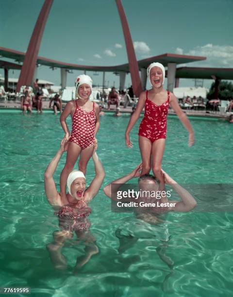 American actress Betty Hutton and hotelier Wilbur Clark stand in the pool of Clark's hotel, the Desert Inn, and hold Hutton's daughters, Lindsey and...