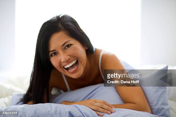 a young woman holds the cushion in her hands as she laughs in front of the camera - chemise de nuit photos et images de collection