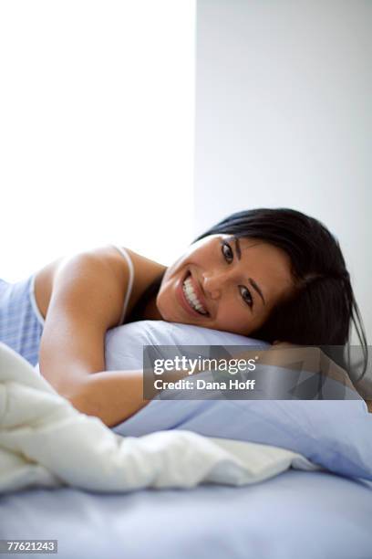 a young woman rests on the cushion as she laughs in front of the camera - negligée stock-fotos und bilder