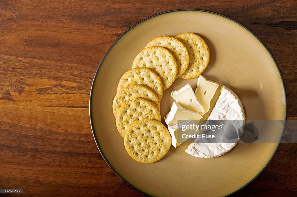 Beige plate of soft cheese and crackers on wooden table